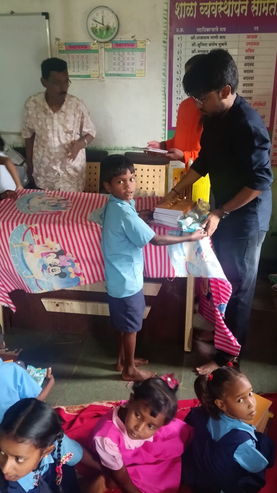 A child receiving educational materials during Rudra Foundation student support work